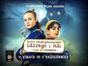 Dwoje dzieci w sportowych kurtkach stojących tyłem do siebie, a w tle pojawia się duży, groźny kot o świecących oczach. Całość utrzymana jest w tajemniczym, nieco mrocznym klimacie.