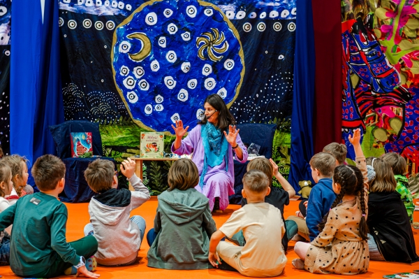 grupa dzieci otacza kobietę, która coś im opowiada