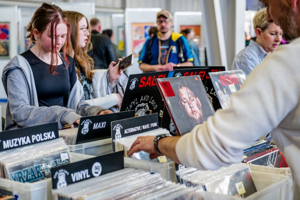 dwie młode dziewczyny i mężczyzna przeglądają stoisko z płytami analogowymi
