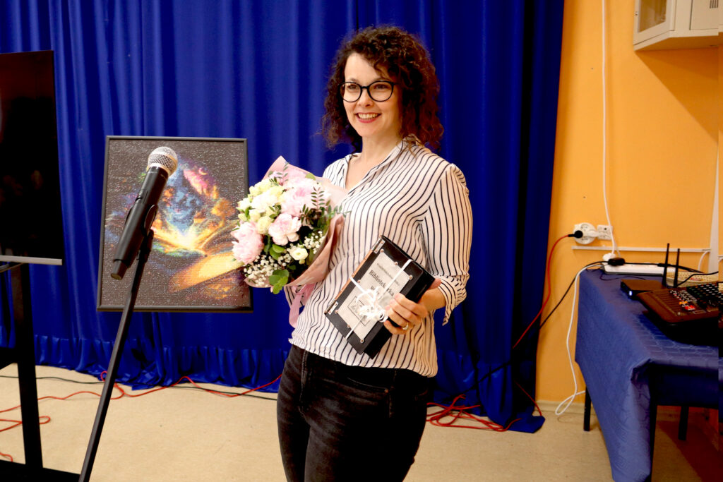 Ewa Michalak ze statuetką Uśmiechnięta kobieta trzyma bukiet kwiatów i statuetkę Warmińsko-Mazurskiego Bibliotekarza Roku 2024