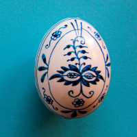 zdjęcie ręcznie malowanej pisanki w granatowe roślinne ornamentyna niebieskim tle.