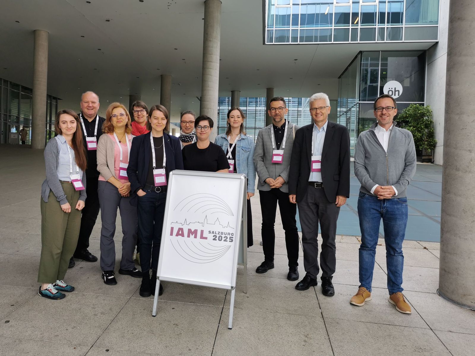 Polska delegacja na Kongresie IAML w Salzburgu Grupa bibliotekarzy stoi przy potykaczu z nazwą konferencji
